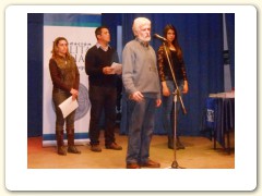 Los conductores de la ceremonia, profesores Rosmary Cardozo y Gabriel Fernandez, junto a la joven Thalía García, asistente de escenario, escuchan al Dr. Gustavo Guadalupe en la apertura del acto.